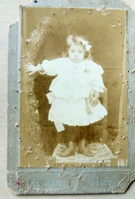 A little girl standing on a chair.