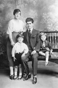 A studio photograph of the parents with their two children.