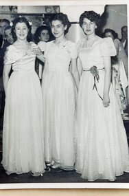Three young women in long evening gowns.