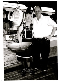 A man and a lady are standing beside their stall at the Victoria Market in MELBOURNE.