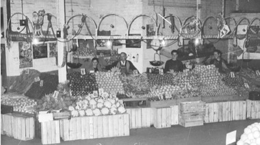 Four people are standing behind a fruit stall, which was in Camberwell Market.