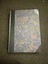 Illustrated hardcover book with dark blue/grey/red/gold marble effect front and back cover. Black leather corners and spine. Title and author's name are embossed in gold on a red background on spine. Also on spine are 13 gold bands and 5 gold decorations. The book has a matching cardboard sleeve.
