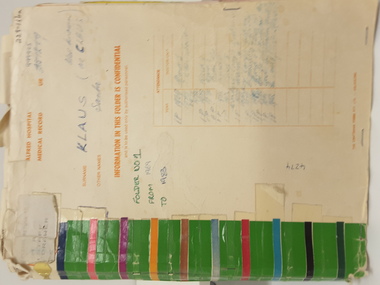 Manilla coloured medical folder with bands of coloured tape along the left hand spine, writing and stamps on the cover.