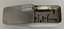 Picture shows a small metal  box containing spaces where the glass syringes and metal needles are housed. 