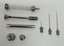 Picture of glass syringe and metal plunger along with a number or reusable needles.