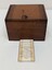 Photo shows the wooden box used to house the brass and glass microscope. Includes a written text regarding the past use of the  microscope.