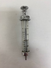 A glass syringe with graduation markings down the side, and a metal end for depressing the plunger and opposite end to attach needles.