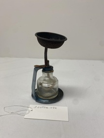 Metal stand containing glass bottle with a wick in the lid. Used to vaporise and deliver medication to patients.