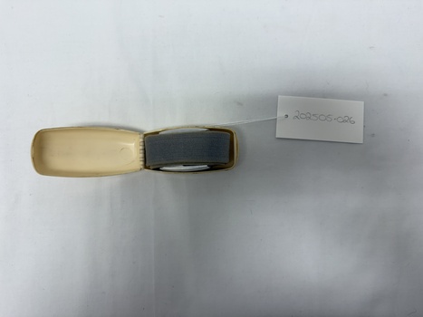 Degraded white plastic case open with fabric and metal tourniquet folded inside