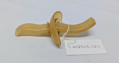 Johnson & Johnson Resusitube airway
An antique yellowed plastic object with curved handles and a central knob, labeled as item 202505.027.