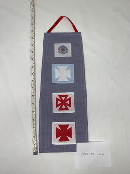 blue and white houndstooth (uniform dress fabric) panel with four badges attached in a row down length of fabric. Each badge represents a level of training and the cap badge