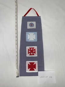 blue and white houndstooth (uniform dress fabric) panel with four badges attached in a row down length of fabric. Each badge represents a level of training and the cap badge