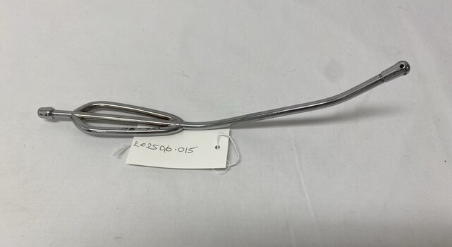 2 piece metal curved tube, with detachable screw on tip. Screw on tip has one hole at the tip and 4 holes equally spaced around the tip. Handle end has 2 rounded pieces of metal additions that form the hand grip. Used to suction oropharyngeal secretions. 