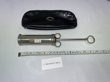 silver metal cylindrical syringe with plunger extended and black vinyl case