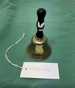 Small brass hand bell with a black wooden handle with a white painted number fifteen.
