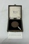 A round bronze medallion in a velvet-lined presentation box with a ribbon, displayed on a white surface with a tag labeled "202509.008.