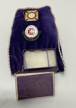 A purple velvet pouch with gold trim holds two vintage pins and an empty purple jewellery box labeled Dumbrells The Jewellers, 319-321 Bourke St, Melbourne, directly opposite Myers. Phone Central 7580.