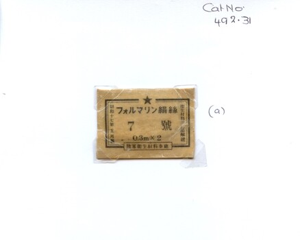Front of packet containing two japanese silk surgical sutures, mounted on white card