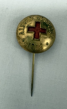 A gold/bronze coloured pin featuring a red enamel cross at its centre, inscribed with "Alfred Hospital" and the year "1918." 
