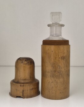 wooden container, with lid beside it, containing a glass bottle 