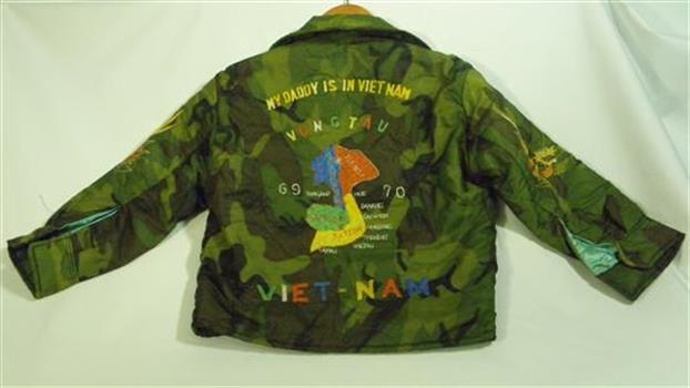 A child's bomber-style jacket made of khaki camouflage print polyester, hand embroidered and lined with blue.