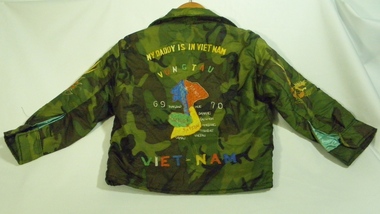A child's bomber-style jacket made of khaki camouflage print polyester, hand embroidered and lined with blue.