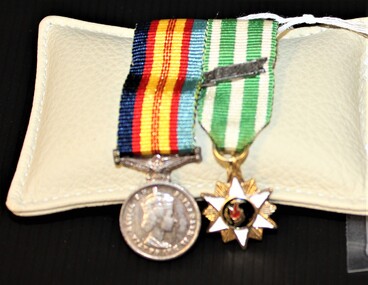 Two miniature Vietnam service medals on striped ribbon. Medal on the left is silver and round, with image of Queen Elizabeth 2. Medal on the right is star-shaped with a map of Vietnam in the centre.  
