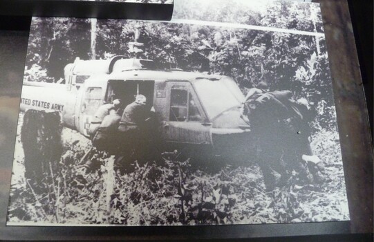 A Black and White Photograph of Soldiers Beside an United States Army Helicopter.