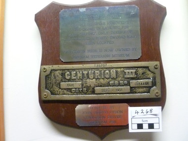 A wooden plaque with three metal plates.