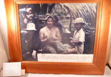 In a Timber Frame is a Coloured Photograph of Pte John Tease with Village Children