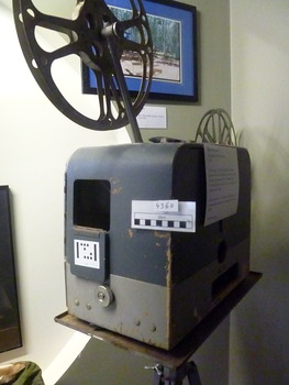 This is a Filmosound GB Bell & Howell film projector c1950 with a tripod stand. 