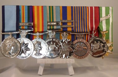 8 medals mounted on pin board for wearing on a jacket.