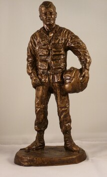 Statue of airman in flying uniform holding helmet under right arm