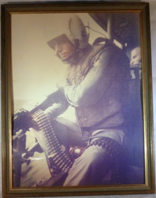 A Framed Colour Photograph of a Soldier in a Huey helicopter. 