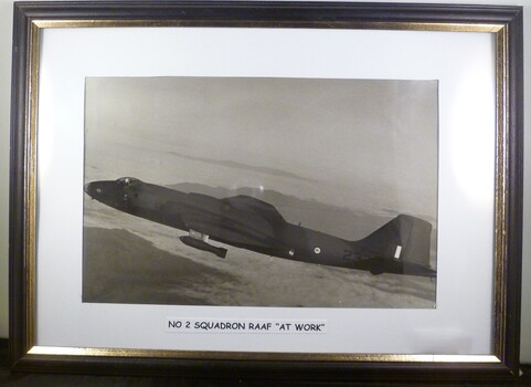 A Framed Black and White Photograph of a Plane in Flight