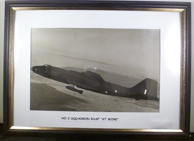 A Framed Black and White Photograph of a Plane in Flight