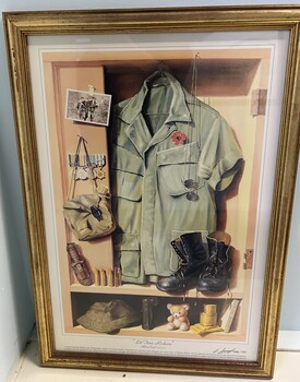 In a Timber Frame is a Coloured Print with a White Matt of Several Items of Clothing and a Black and White Photograph.