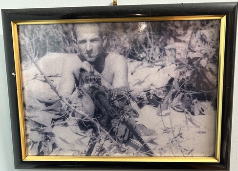 A Framed Black and White Photograph of A Soldier Without His Shirt On Holding a M60 Machine Gun