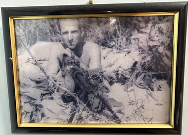 A Framed Black and White Photograph of A Soldier Without His Shirt On Holding a M60 Machine Gun