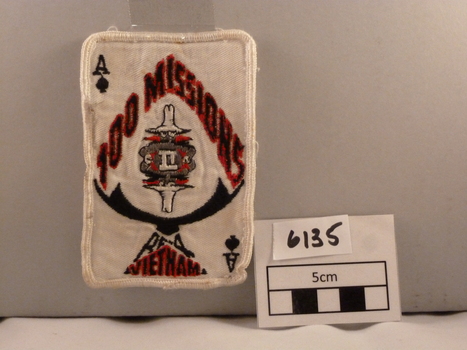 Rectangular woven cloth badge signifying '100 Missions in Vietnam' white, red and black.