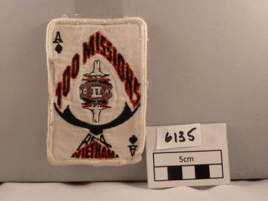 Rectangular woven cloth badge signifying '100 Missions in Vietnam' white, red and black.