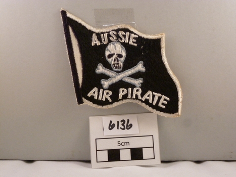 Woven cloth badge black, white & grey, flag shaped.