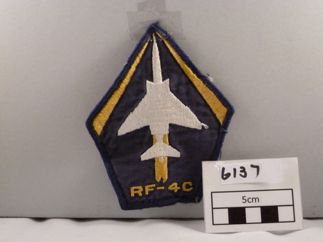 Woven cloth badge coloured, blue, white, yellow diamond shaped.