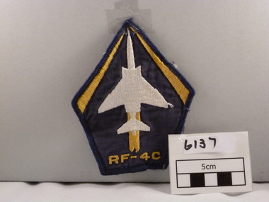 Woven cloth badge coloured, blue, white, yellow diamond shaped.
