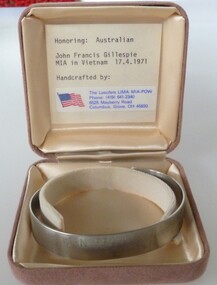 Stainless steel open ended bracelet with missing serviceman's full name and date missing. In a buff square satin lined box.