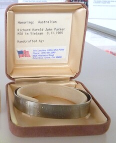 Stainless steel, open-ended bracelet engraved with the missing serviceman's full name and date missing in a buff square velvet satin-lined box.