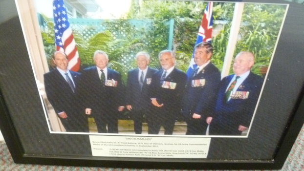 A Black Framed Coloured Photograph of Bayne (Gus) Kelly receiving US Commendation Medal - September 2011