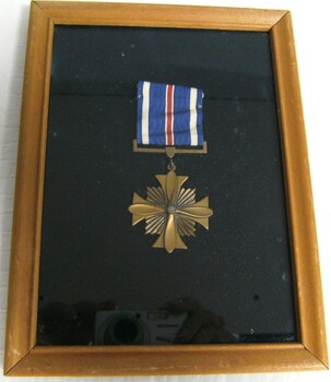 Distinguished Flying Cross medal in a wooden frame with glass front.