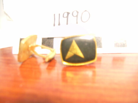 Black onyx on gold setting. Image in gold of two triangles one large and one small.