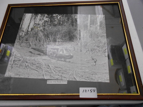 Black and white photograph of soldiers alighting from a United States Army helicopter in the jungle.